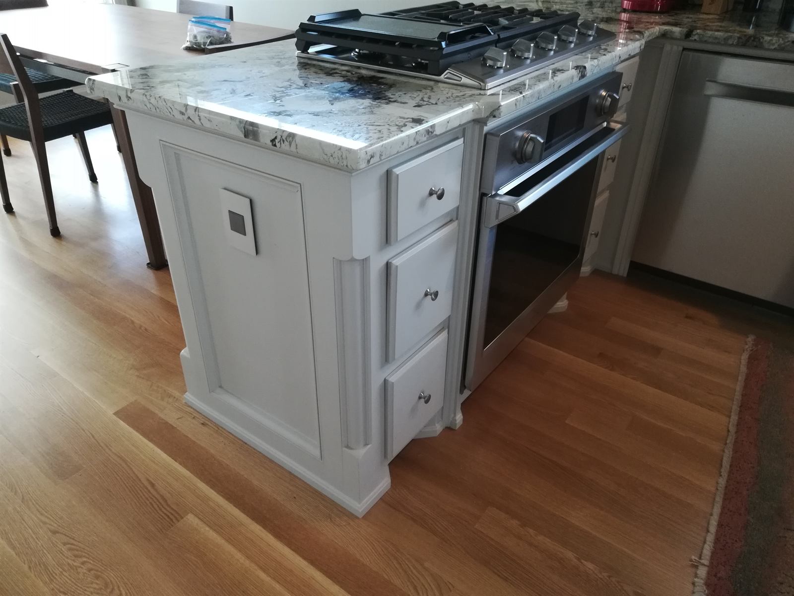 Custom white painted kitchen island with cooktop, applied molding, and granite countertop