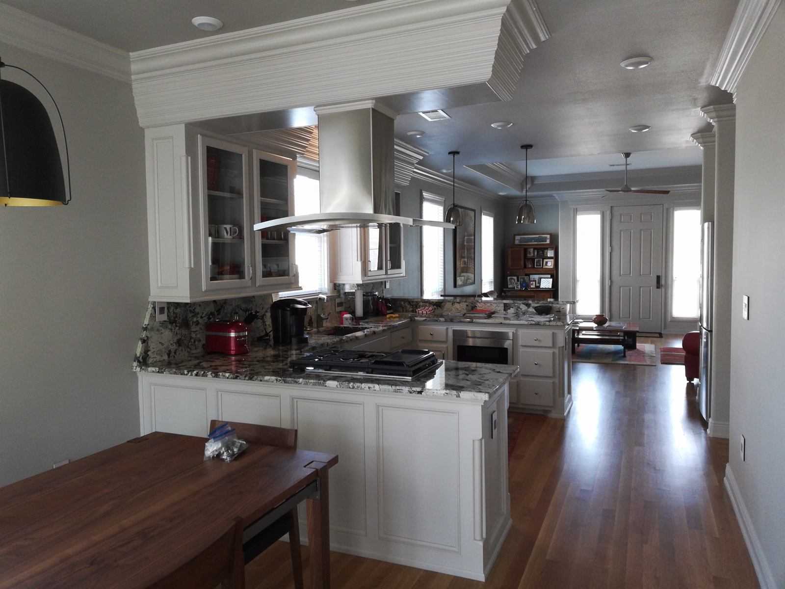Custom white shaker kitchen with granite countertops, glass-front upper cabinets, and stainless hood