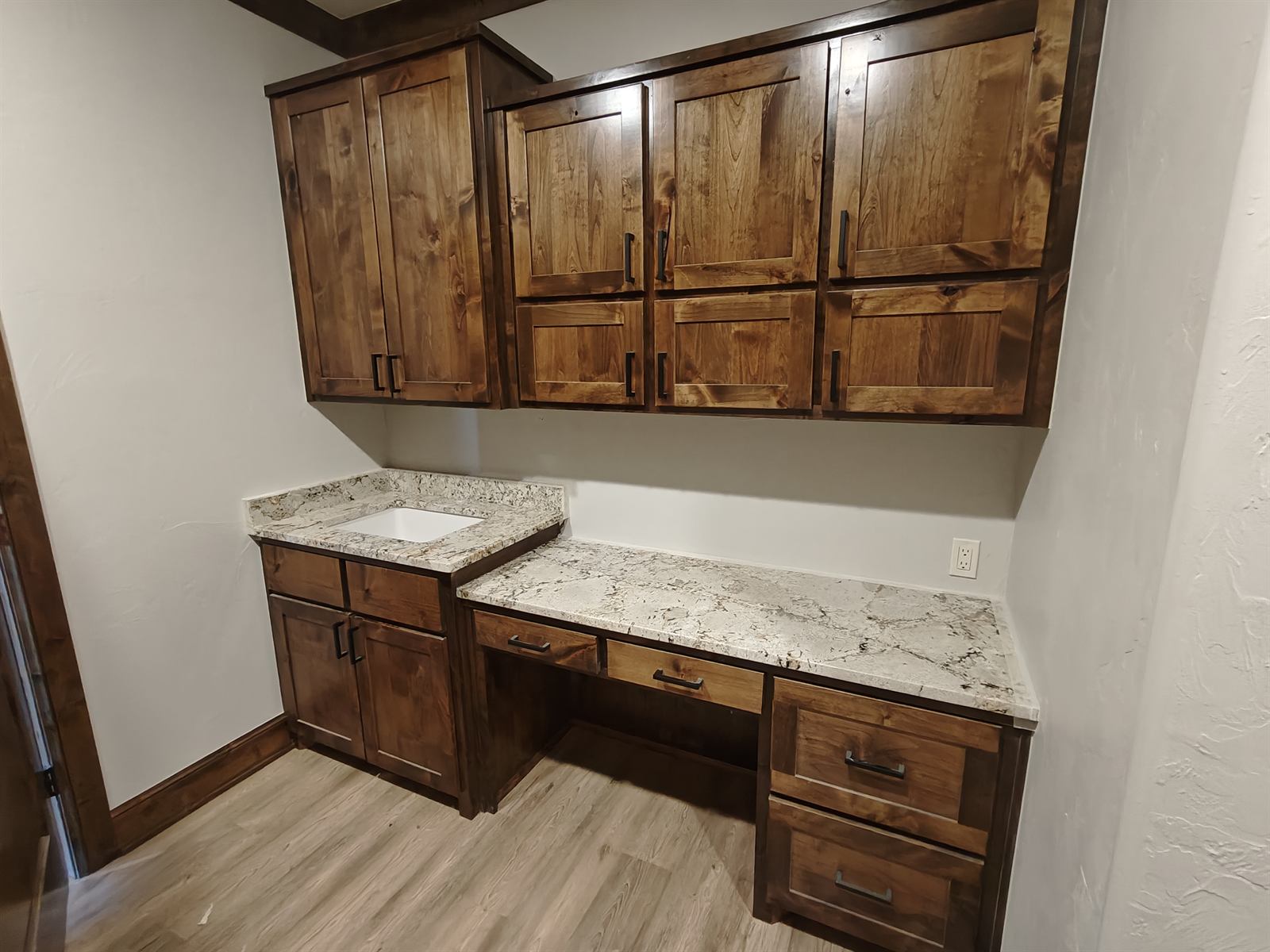 Custom dark-stained home office built-in desk with upper cabinets and granite top
